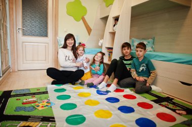 Mutlu bir aile birlikte eğleniyor, dört çocuk ve bir anne evde twister oynuyor..