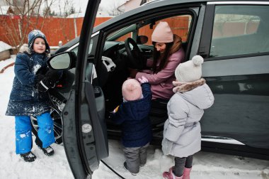 Çocuklu genç bir anne evinin bahçesinde elektrikli araba şarj ediyor. . 