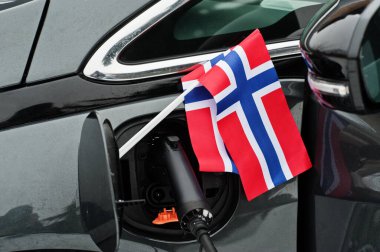Norveç bayrağı ekolojik araba konsepti. Bir güç tedarikçisini fişe takmak, modern otomobili şarj etmek.