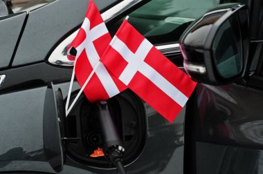 Danimarka bayrağı ekolojik araba konsepti. Bir güç tedarikçisini fişe takmak, modern otomobili şarj etmek.