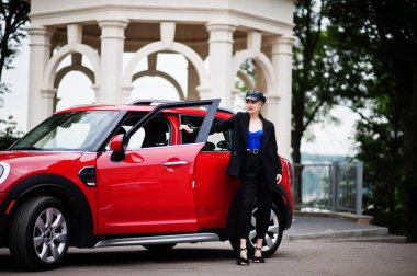 Şapkalı, siyah, mavi korseli, kırmızı şehir arabasının yanında parlak makyajlı güzel, sarışın, seksi kadın modelin portresi.. 