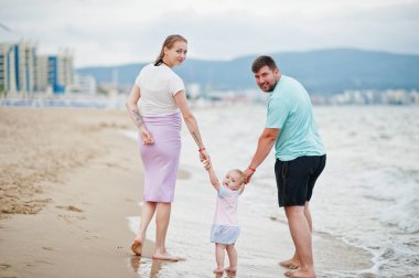 Yaz tatilleri. Ebeveynler ve insanlar çocuklarla birlikte dışarıda faaliyet gösteriyor. Mutlu aile tatilleri. Baba, hamile anne, küçük kız deniz kumsalında.. 