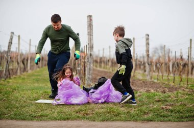 Üzüm bağlarını temizlerken çöp torbası toplayan bir aile. Çevresel koruma ve ekoloji, geri dönüşüm.