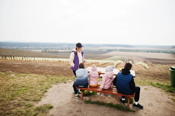 Çocuklu annem üzüm bağına karşı tahta masada oturuyor..