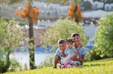 Türkiye 'de çimenlerde oturan üç çocuk palmiyelere yaslanıyor.