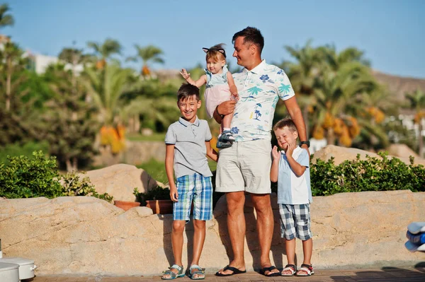 Father with three kids on Turkey resort against palms.