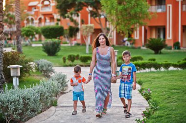 Mısır tatil köyünde yürüyen iki oğlu olan bir anne. Aile tatili.
