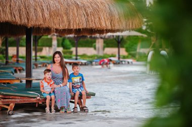Anne ve iki oğlu Mısır 'da havuz kenarında güneşlenmişler. Aile tatili.