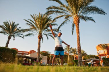 Mısır tatil köyü bahçesinde palmiyelerin yanında duran komik adam..