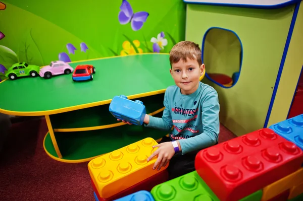 Cute boy playing in indoor play center. Builds with constructor bricks.