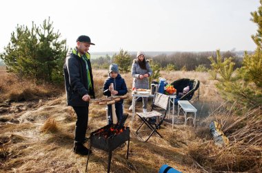 Çam ormanında bir güvertede aile barbeküsü. Izgarayla barbekü günü.