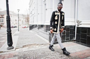 Geleneksel ceket giymiş mega stil Afrikalı bir adam. Şapkalı, güneş gözlüklü, elinde puro olan şık siyahi bir adam..