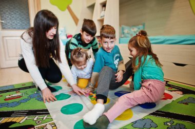 Mutlu bir aile birlikte eğleniyor, dört çocuk ve bir anne evde twister oynuyor..