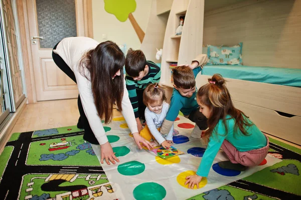Mutlu bir aile birlikte eğleniyor, dört çocuk ve bir anne evde twister oynuyor..