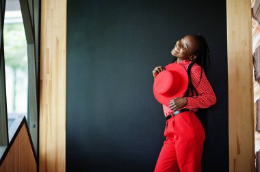 Pretty braids business african american lady bright bossy person friendly wear office red shirt, hat and trousers. 