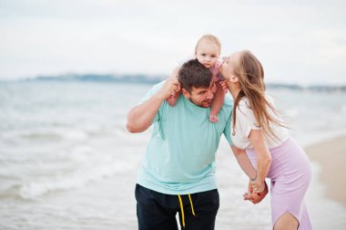 Yaz tatilleri. Ebeveynler ve insanlar çocuklarla birlikte dışarıda faaliyet gösteriyor. Mutlu aile tatilleri. Baba, hamile anne, küçük kız deniz kumsalında.. 