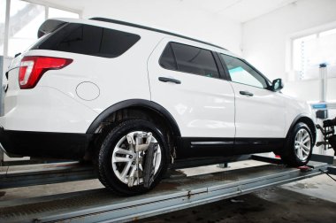 Amerikan SUV aracı, servis istasyonunun atölyesinde tekerlek hizalama kamerasını kontrol ediyor..