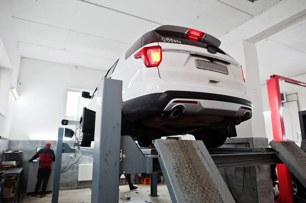 Amerikan SUV aracı, servis istasyonunun atölyesinde tekerlek hizalama kamerasını kontrol ediyor..