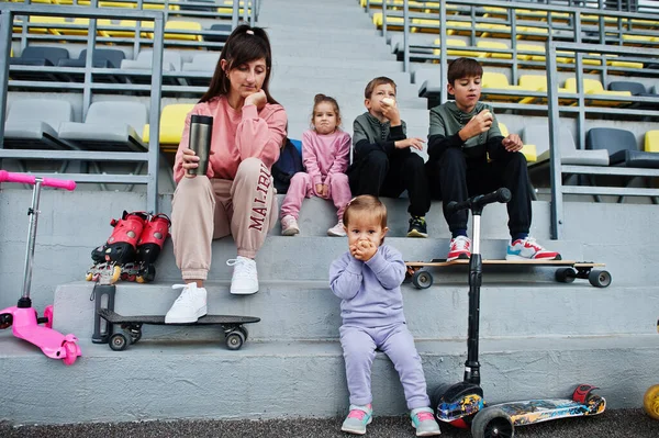 Młoda Stylowa Matka Czwórką Dzieci Siedząca Sportowym Podium Stadionie Jedząca — Zdjęcie stockowe