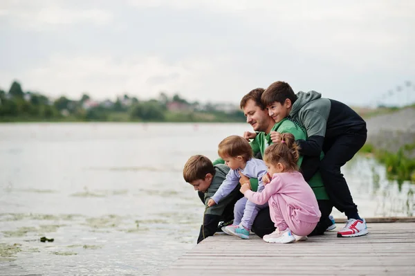 Father love. Dad with four kids outdoor on the pier. Sports large family spend free time outdoors.