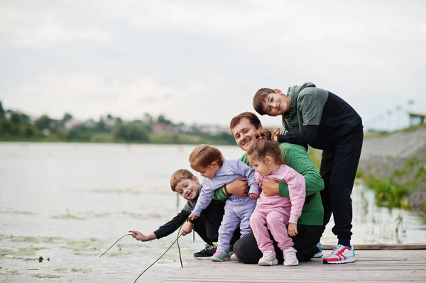Father love. Dad with four kids outdoor on the pier. Sports large family spend free time outdoors.