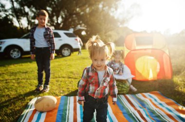 Dört çocuk birlikte vakit geçiriyor. Açık hava piknik battaniyesi. Kareli tişörtlü küçük tatlı kız..