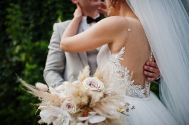 Bride and groom holding beautiful tender wedding bouquet.