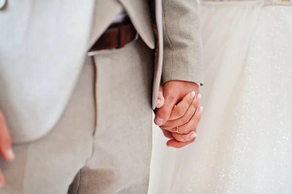 Bride and groom holding hands, close up. Their happy wedding day.