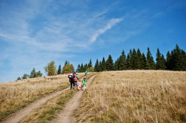 Woman is traveling with a childrens. Mom in the mountains. Climb to the top of the mountain with children. With the backpack climbed to the top.