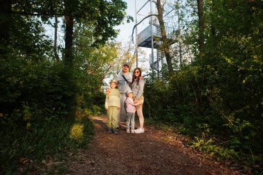 Family with kids against viewing tower at Brno, Czech Republic. Watchtower during sunset with trees.