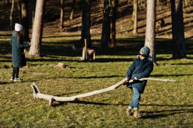Boy pulls a tree in spring sunny park.
