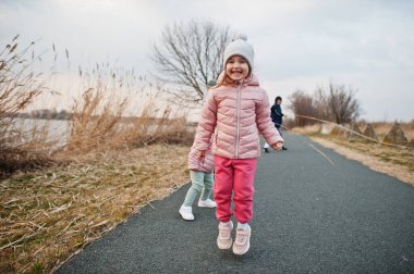 Children jump on the path by the lake.