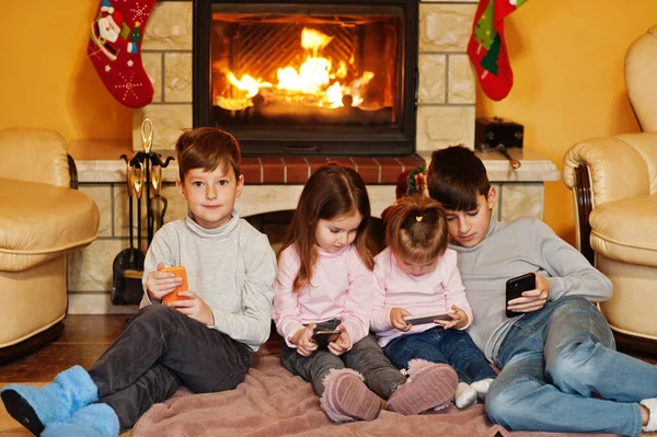 Щасливі Четверо Дітей Дивляться Мобільний Телефон Вдома Біля Каміна Теплій — стокове фото