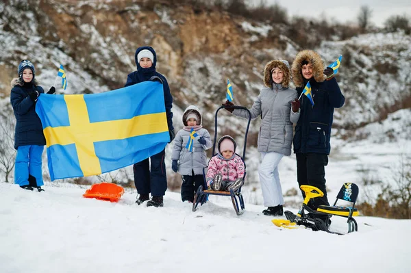 Scandinavian family with Sweden flag in winter swedish landscape.