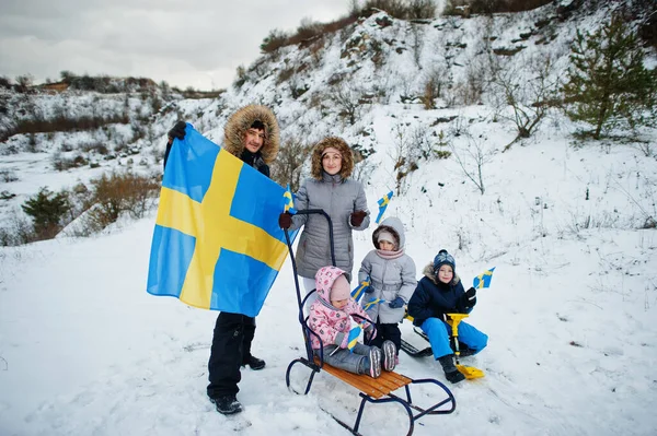 Scandinavian family with Sweden flag in winter swedish landscape.