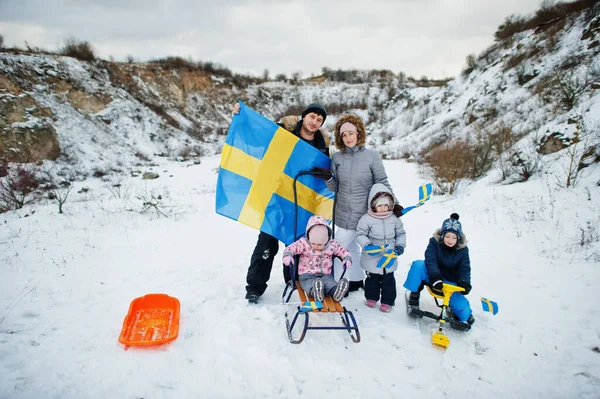 Scandinavian family with Sweden flag in winter swedish landscape.