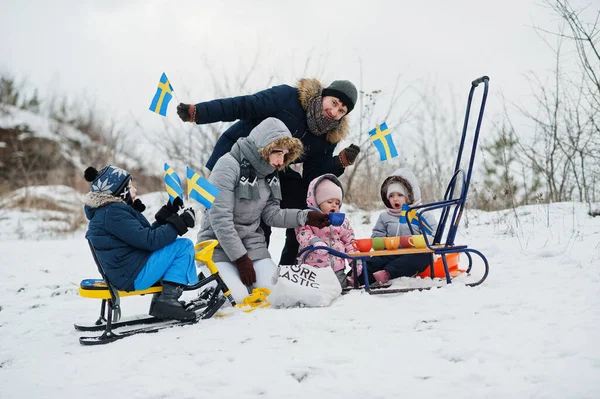 Scandinavian family with Sweden flag in winter swedish landscape.