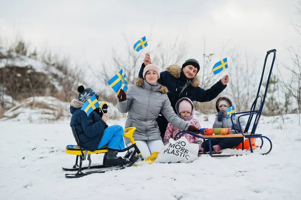 Scandinavian family with Sweden flag in winter swedish landscape.