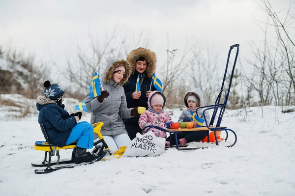 Scandinavian family with Sweden flag in winter swedish landscape.