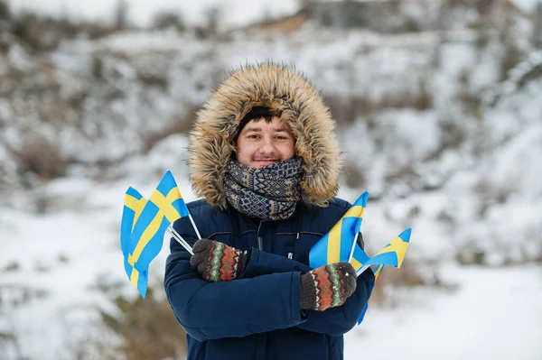 Scandinavian man with Sweden flag in winter swedish landscape.