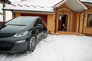 Kışın evin bahçesinde elektrikli araba şarj etmek..