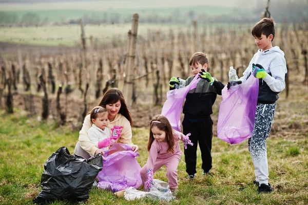 Family with trash bag collecting garbage while cleaning in the vineyards . Environmental conservation and ecology, recycling.