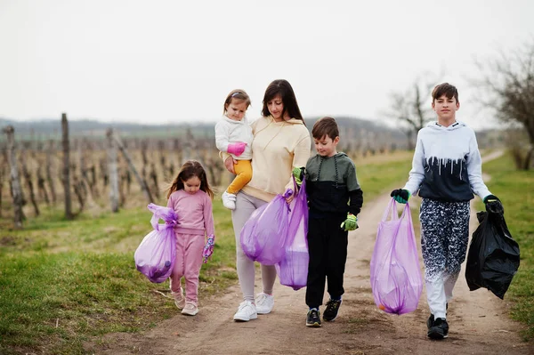 Family with trash bag collecting garbage while cleaning in the vineyards . Environmental conservation and ecology, recycling.