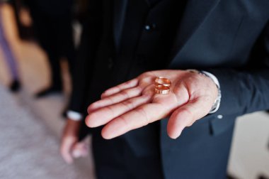 Groom holding wedding rings in hand. 