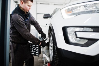 Auto mechanic sets american SUV car for diagnostics and configuration camber check in workshop of service station..