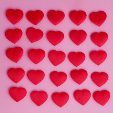 Pembe arka planda kare şeklinde 25 küçük kırmızı kumaş kalp. Sihirli aşk şekerlerini anımsatıyor. Romantik ve şık yumuşak pembe arka plan.