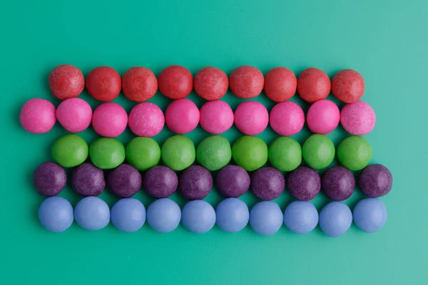 Tatlı Renkli Yuvarlak Şeker Sıraları Her Biri Yeşil Arka Planda — Stok fotoğraf
