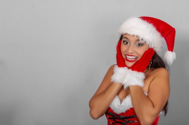 Noel Baba gibi giyinmiş, elleri yüzlerinde ve mutlu bir ifadeyle güzel, esmer bir Latin.