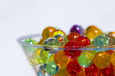 Seçici odaklı yakın plan çekimde renkli jel boncuklar, cam kap, arkaplan veya doku konseptine yerleştirilir
