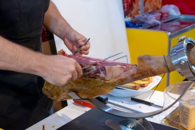Tüm Serrano jambonunu kemikle dilimlemek için profesyonel dilimleyiciyi yakın çekim yap.